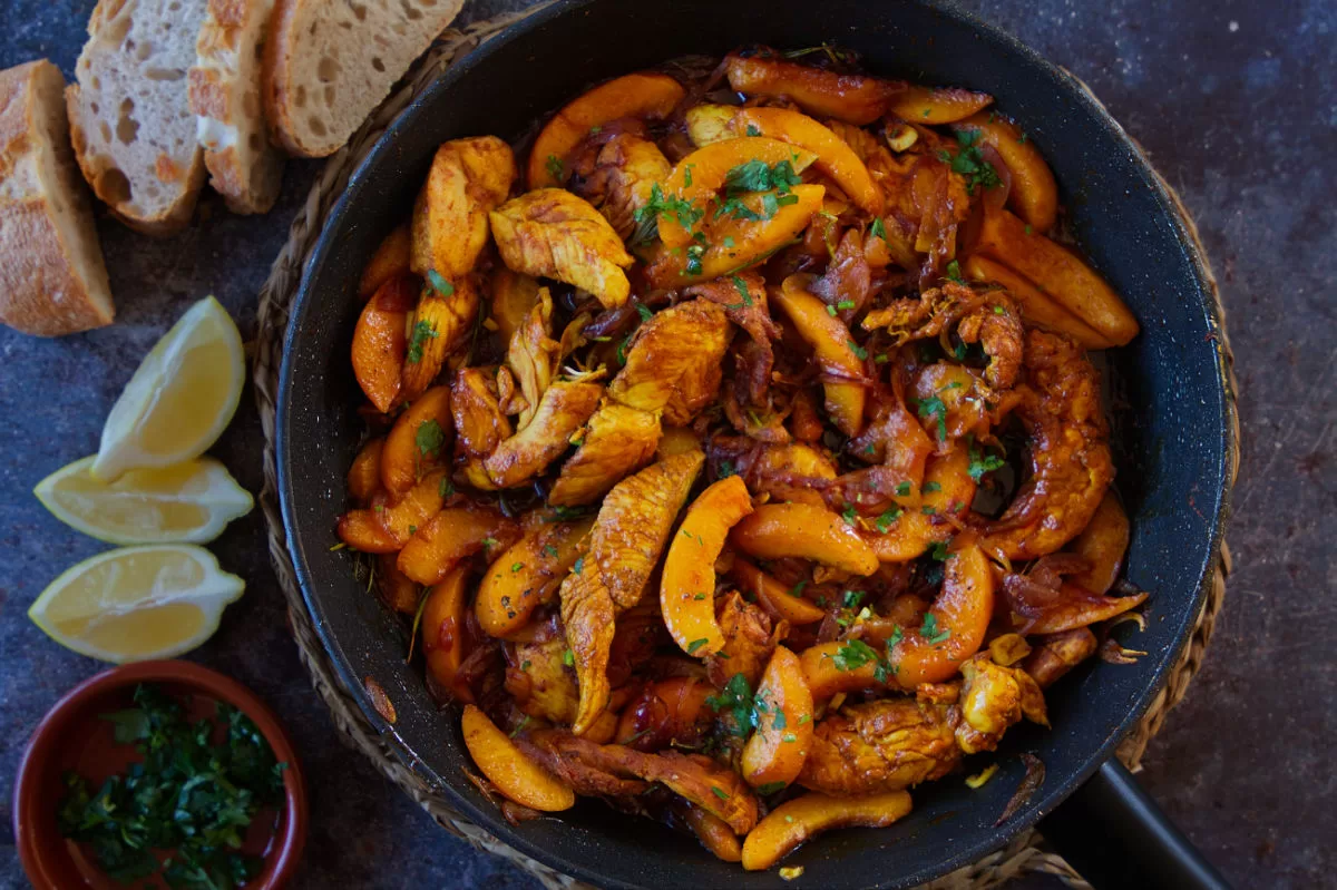 A large pan of chicken with peaches cooked in sherry.