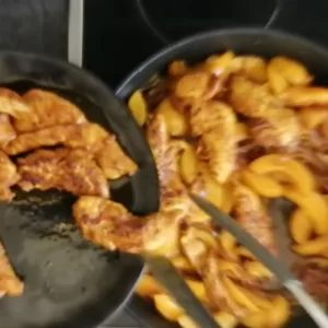 chicken pieces are added to peach and onion slices simmering in a pan.