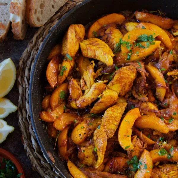 A large pan of chicken with peaches cooked in sherry.