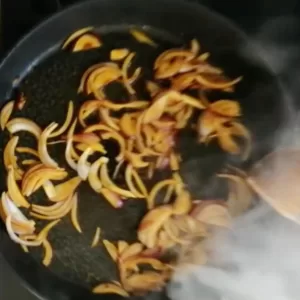 some fried red onnion slices cooks in peach juices.