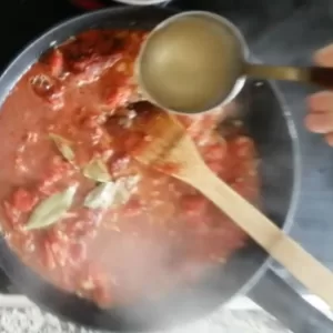 Stock added to a pan simmering with tomato, onion, and garlic