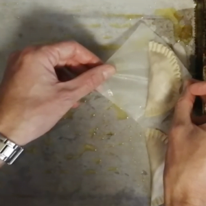 a finished empanada is added to baking tray