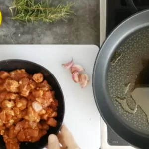 oil in a pan next to some marinated pork pieces