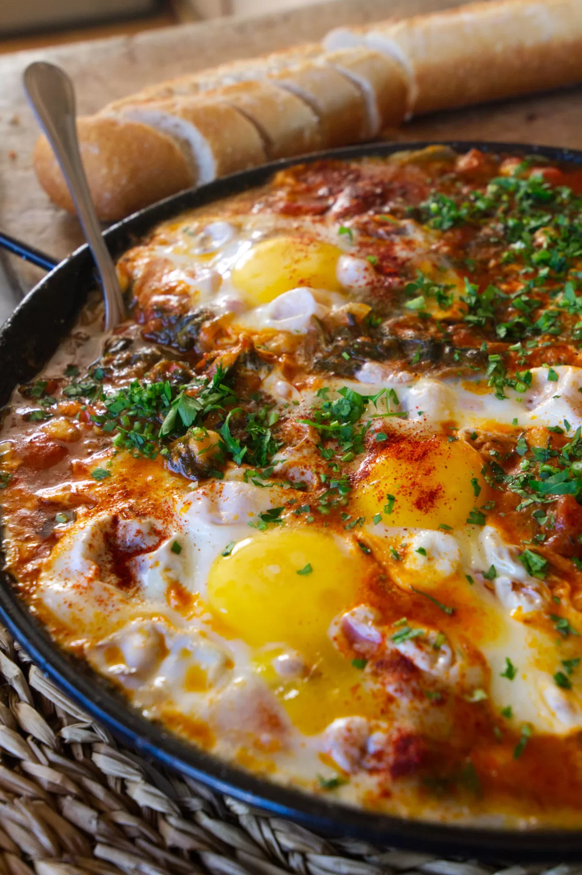 a pan of chickpeas with spinach and eggs is being served.