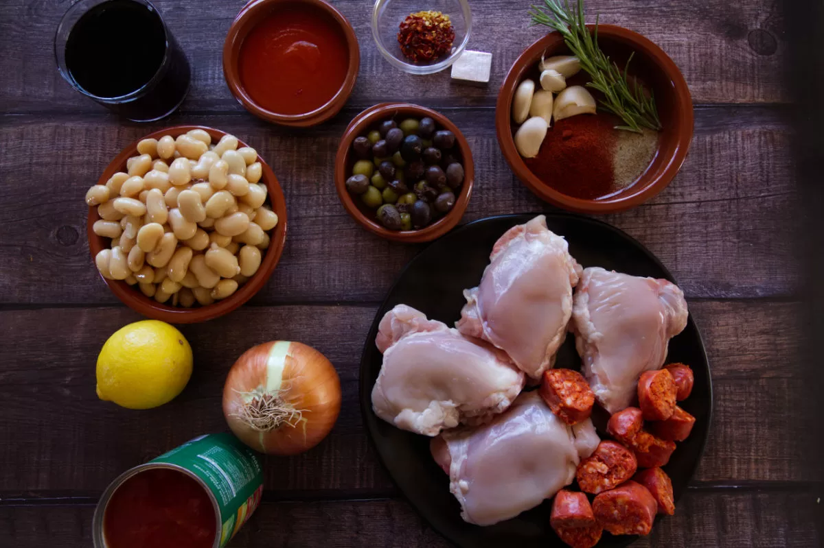 Ingredients for Spanish chicken with chorizo and wine are laid out on a kitchen counter.