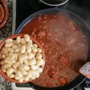 A small bowl of broad beans are added to the sauce.