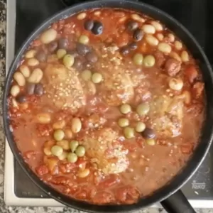 Olives are added to a pan of Spanish Chicken with cchorizo and wine.