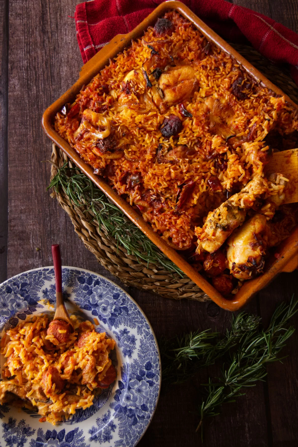 A large dish of spicy chicken, chorizo, and ricce sits beside a small bowl serving