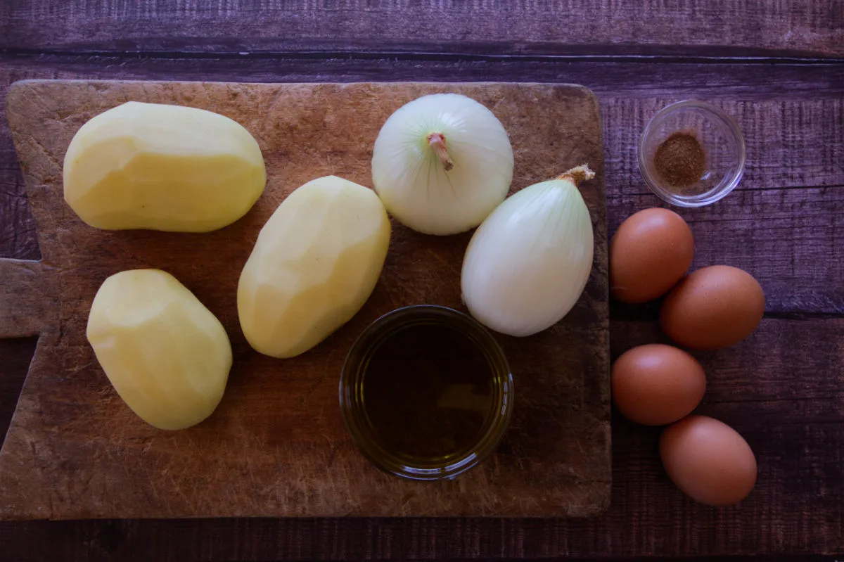 ingredients used to make tortillla are laid out on a wooden counter. 