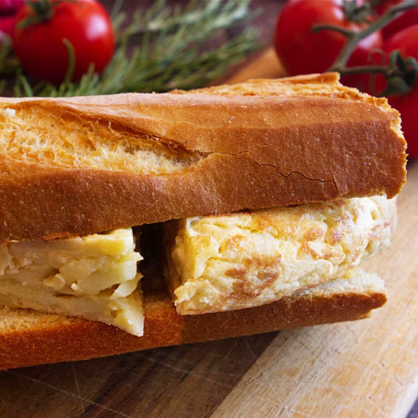 A bocadillo de tortilla is served on a wodden chopping board