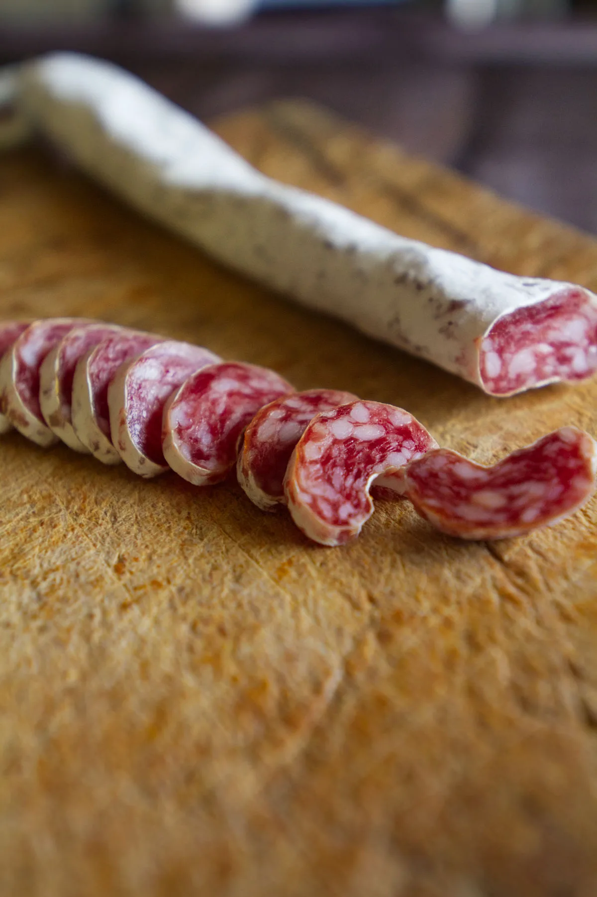 Some hard cured chorizo sits sliced on a chopping board. 