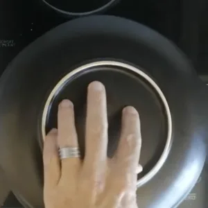 a black plate is laid over a pan with cokked tortilla ready to flip the tortilla.