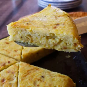 a large slice of tortilla is taken from a freshly cooked tortilla.