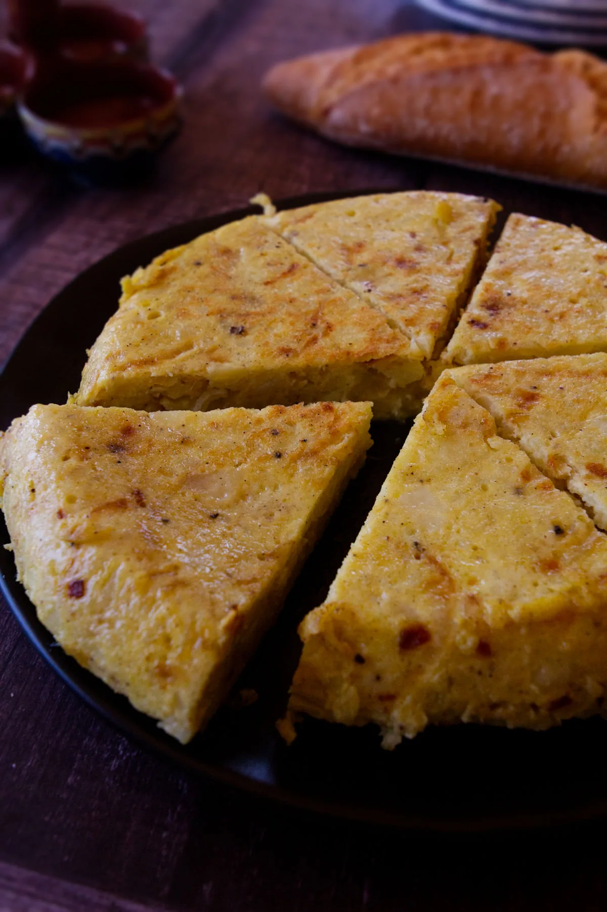 A tortilla sits on a chopping board cut into slices. 