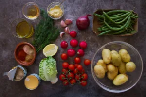 Ingedients used to make a no-mayo potato salad are alid out on a granite table top.