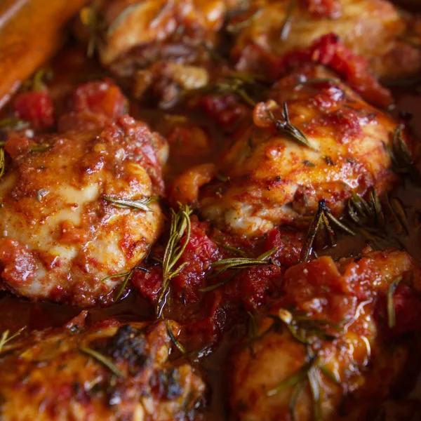 Roast chicken thighs cooked in a red wine, tomato, and herb sauce.