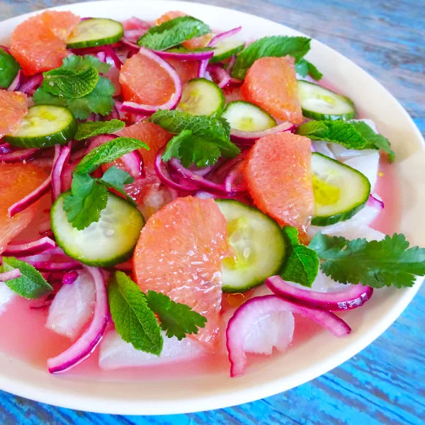 a large plate of colorful bacalao ceviche with pink grapefruit sits waiting to be served