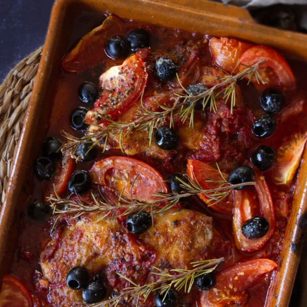 A large casserole dish of Mediterranean boneless chicken thighs with a rich red sofrito sauce.