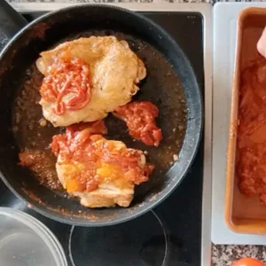 Some chicken browns in a pan with a little sofrito sauce added.