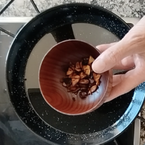 Some browned garlic is removed from a pan of oil.