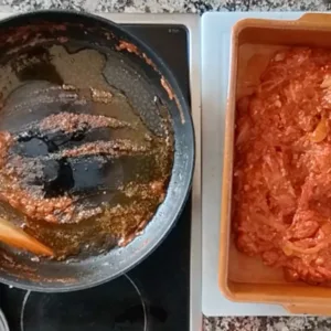 A sofrito sauce is tranferred from a pan into a casserole dish.