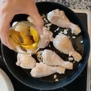 Browned chicken in a pan with some garlic and olive oil