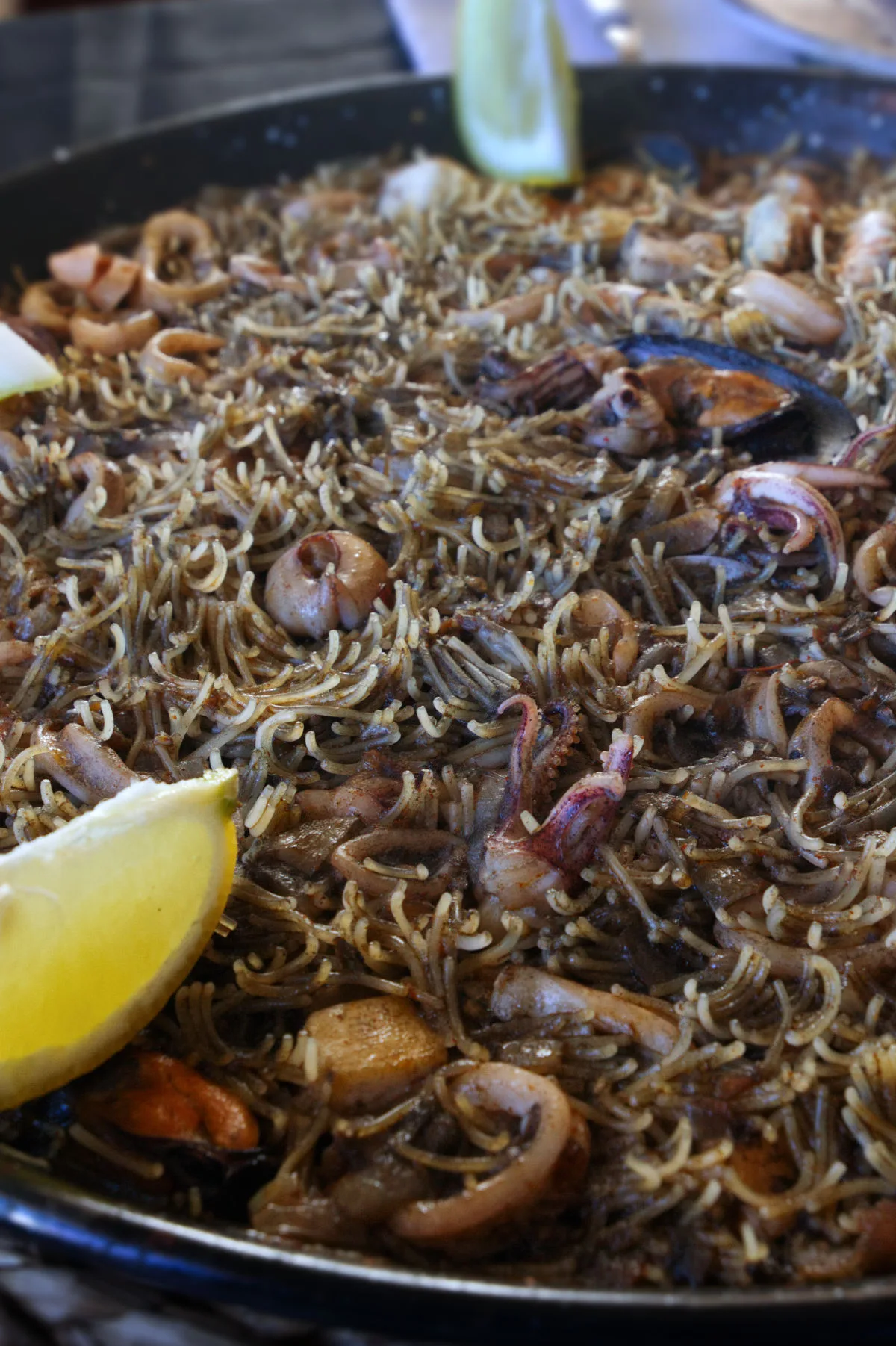 Fideua negra with seafood in a large pan.