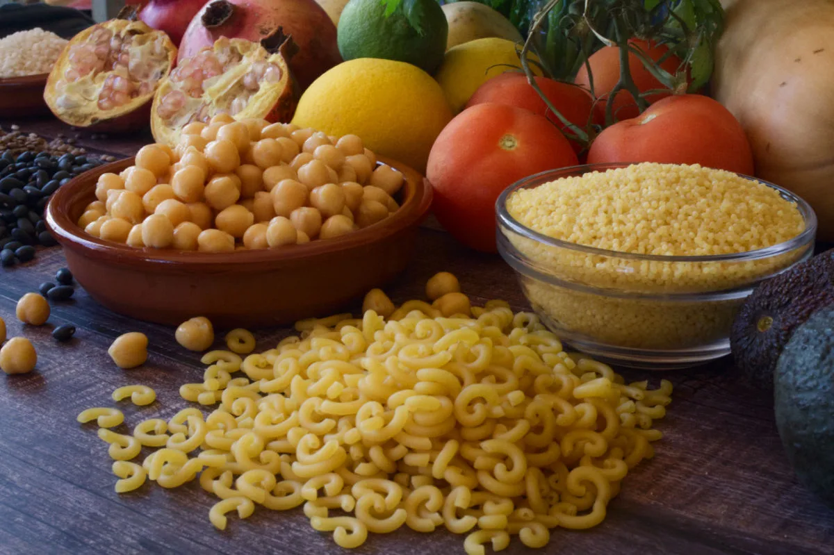 pasta, chickpeas, and some fresh vegetables sit on a countertop.