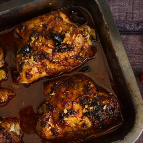 A tray of oven-baked spicy Mediterranean chicken thighs.