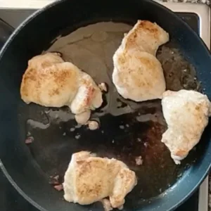 Browned chicken thighs in a pan.