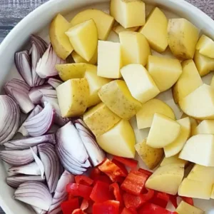 A dish of diced potatoes, bell pepper, and red onion.