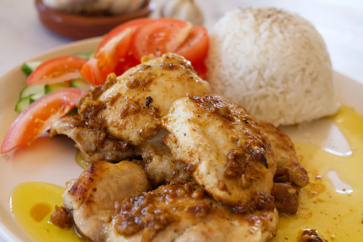 Boneless chicken thighs served on a plate and drizzled with garlic and oil.