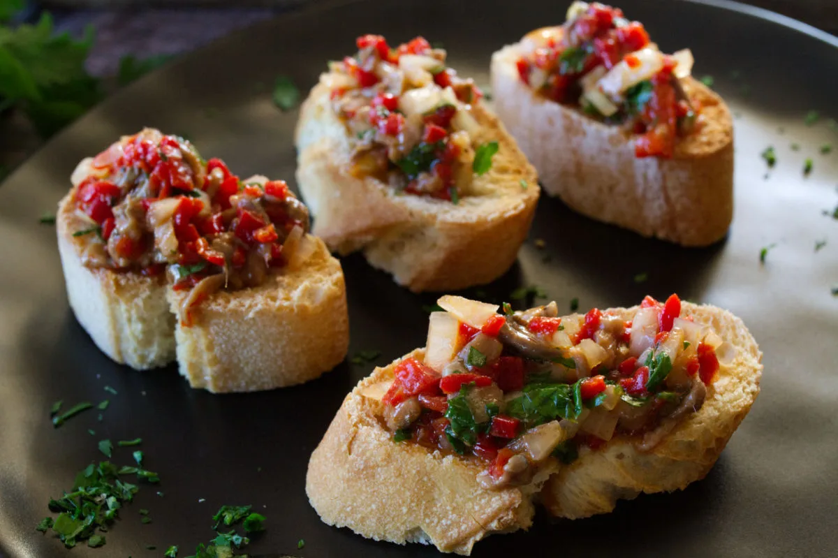 A plate of anchovy and pepper spread on some slices of toasted bread.