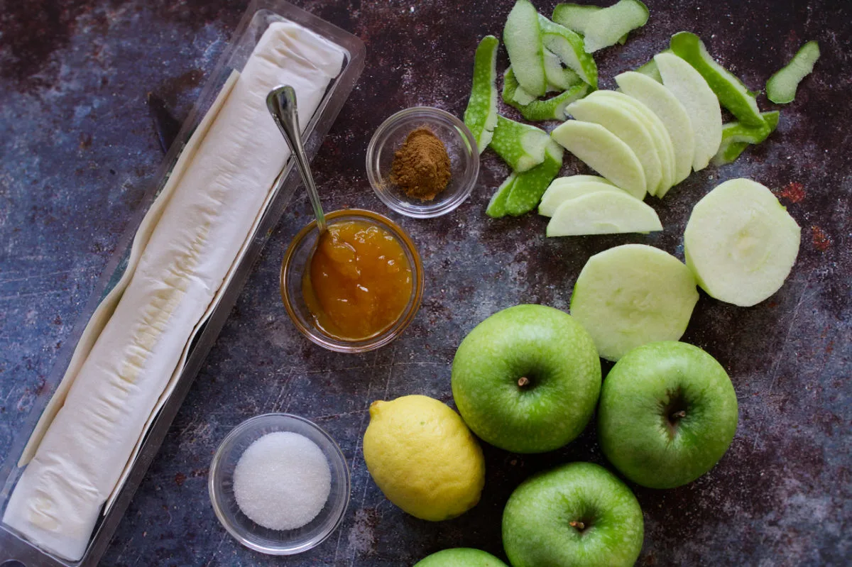 Apple tart ingredients are laid out on a kitchen countertop. 