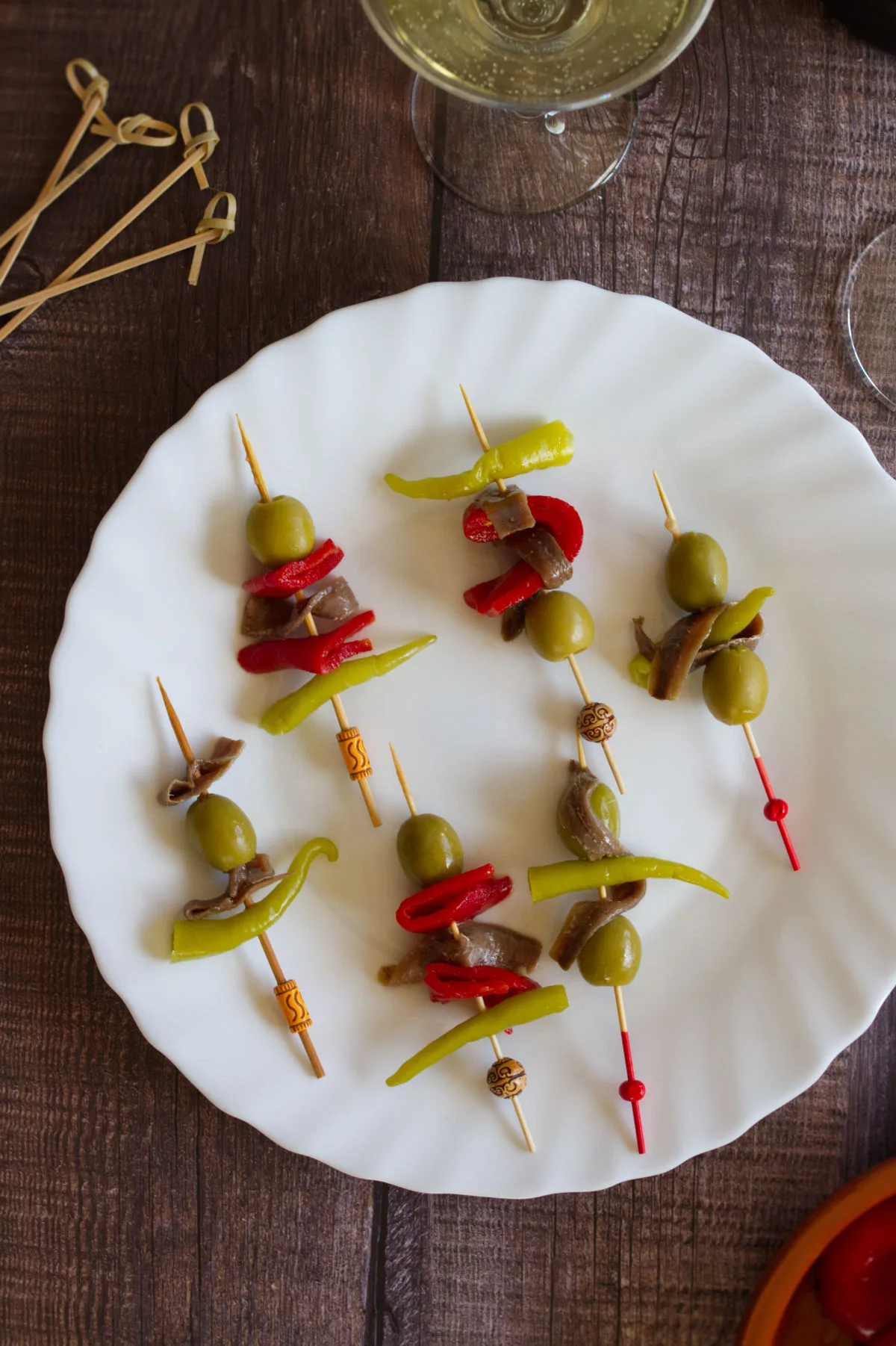 A plate of banderillas sit beside some cocktail glasses.