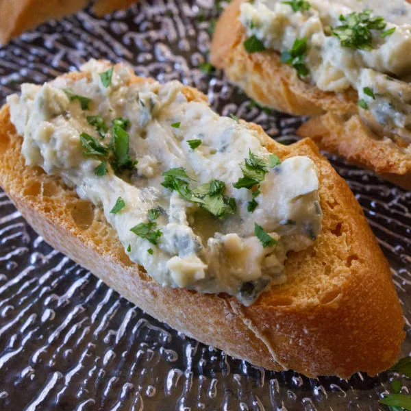 Some tapas servings of blue cheese and cherry spread served on top of toasted bread.