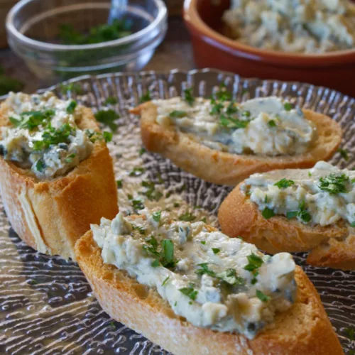 Some tapas servings of blue cheese and cherry spread served on top of toasted bread.