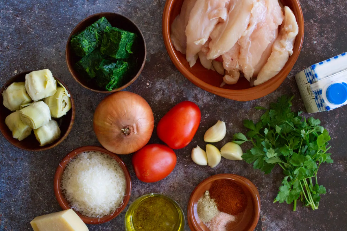 Ingredients for making artichoke chicken sit on a kitchen counter.