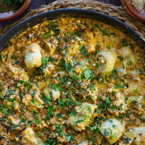 A pan of creamy artichoke casserole with spinach and paprika.