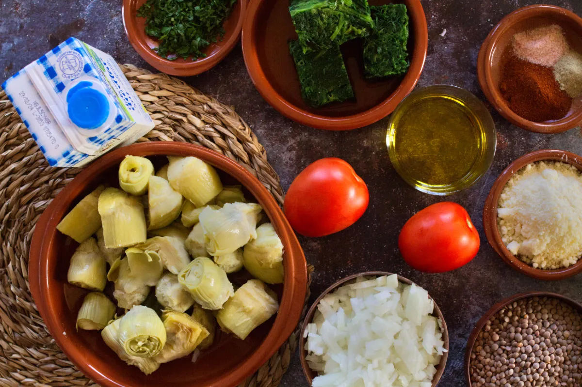 Ingredients for making creamy artichoke and spinach casserole sit on a counter.