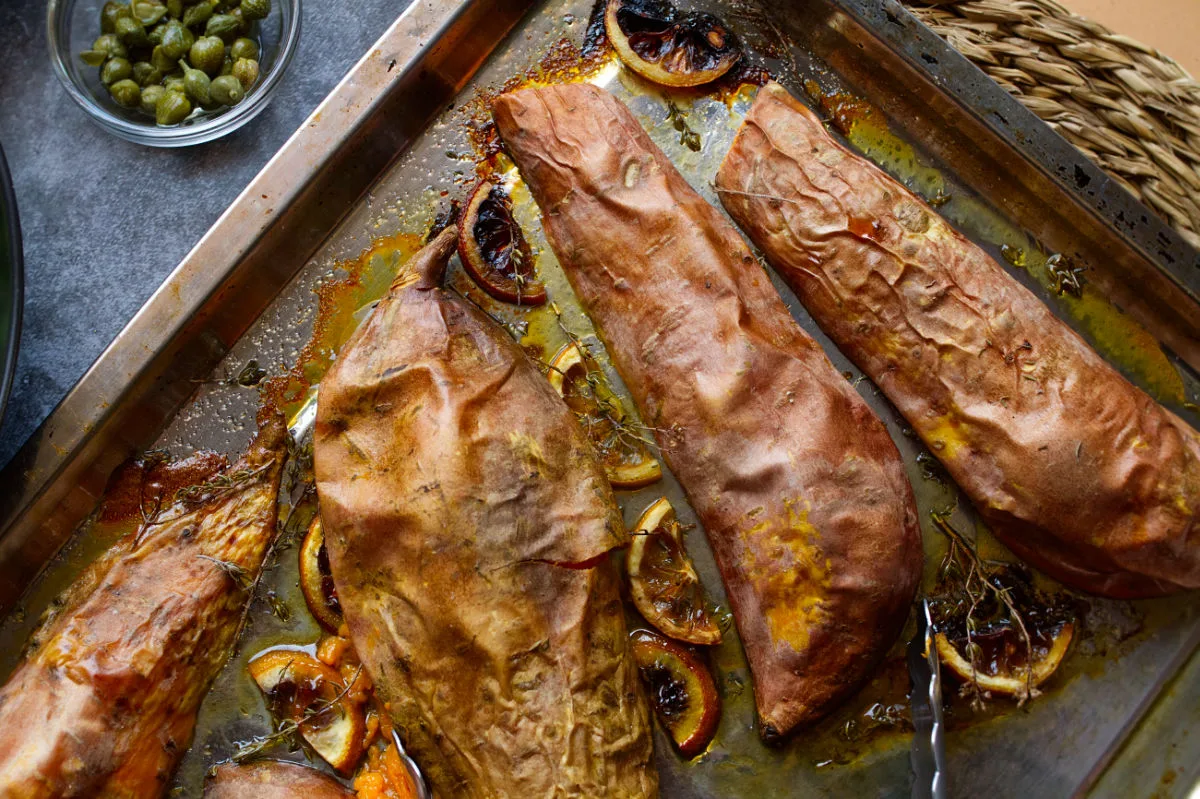 A sheet pan of baked sweet potatoes with lemon and thyme. 