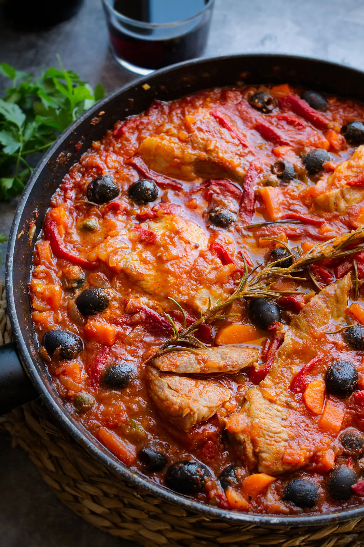 A large pan of Spanish pork secreto garnished with fresh roasemary and black olives.