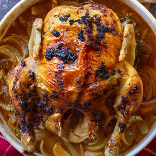 A Spanish roast chicken with a smoked paprika rub sits cooked in a large dish.