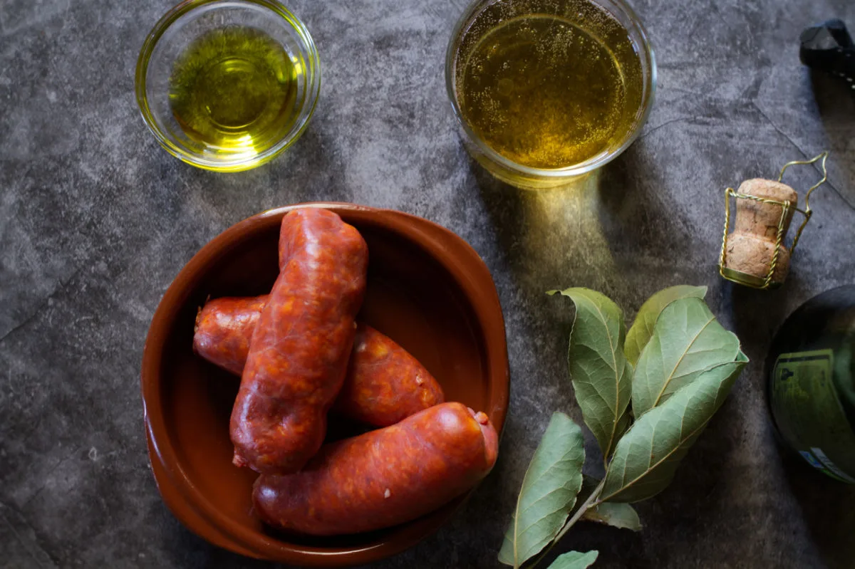 Fresh Spanish chorizo sits beside some Asturian cider and bay laves. 