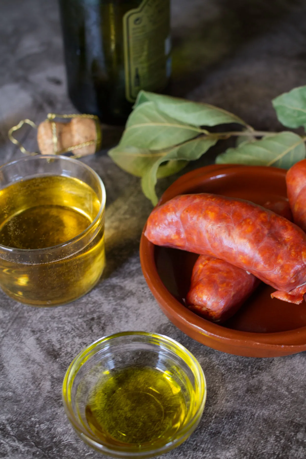 Fresh Spanish chorizo sits beside some Asturian cider and bay laves.