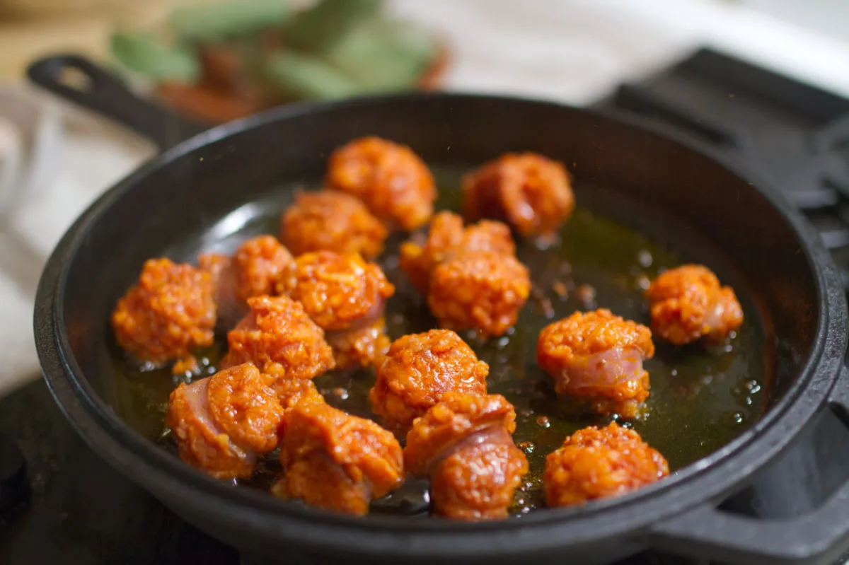 A cast iron pan with some pieces of cooked chorizo sausage. 