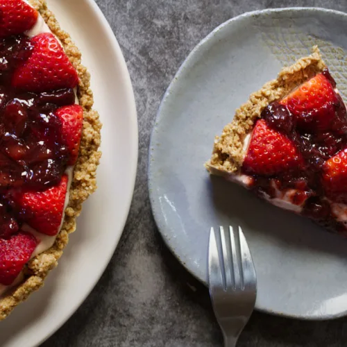 A slice of a no-bake strawberry cheesecake sits beside a fork.