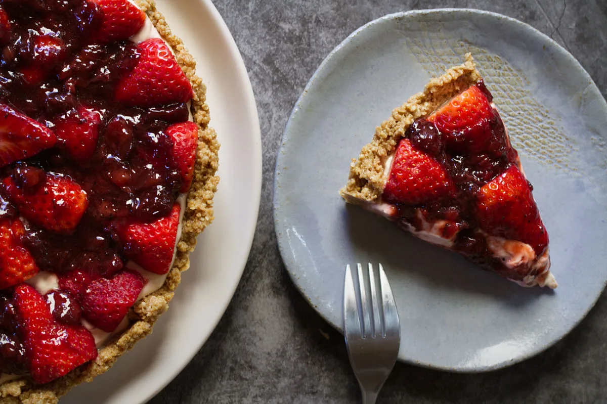 A slice of a no-bake strawberry cheesecake sits beside a fork.