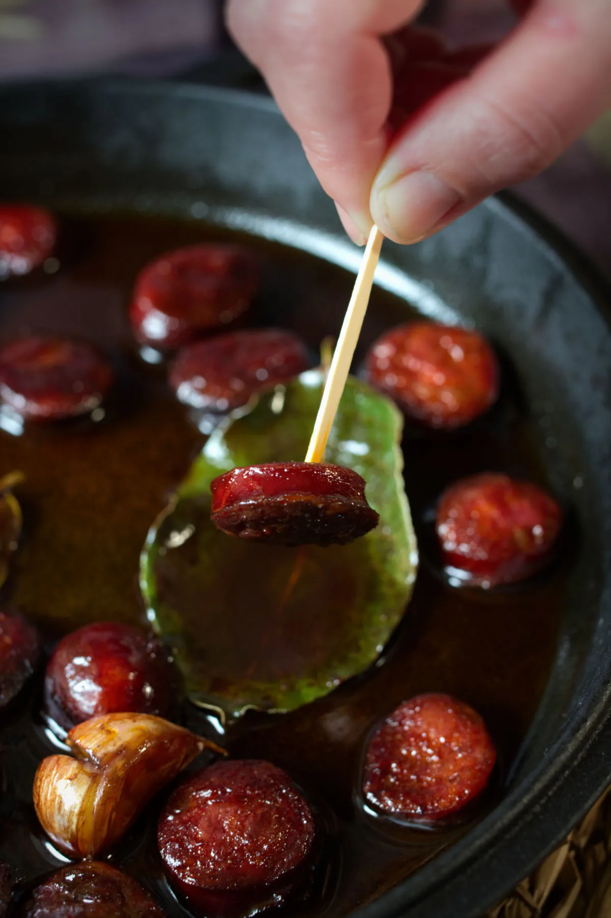 A toothpick skewers a piece of chorizo cooked in red wine